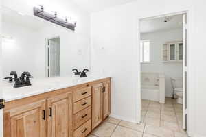 Bathroom with dual vanity, tile patterned flooring, and toilet