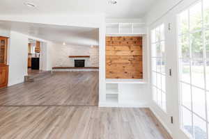 Mudroom with vaulted ceiling, a stone fireplace, light hardwood / wood-style flooring, and a healthy amount of sunlight