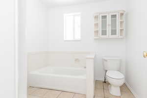 Bathroom featuring tile patterned flooring, a bath, and toilet