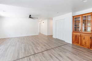 Unfurnished living room with light hardwood / wood-style flooring, a textured ceiling, and ceiling fan