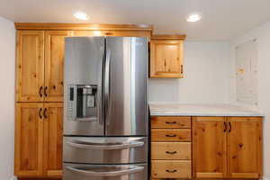 Kitchen with electric panel, light stone counters, and stainless steel refrigerator with ice dispenser