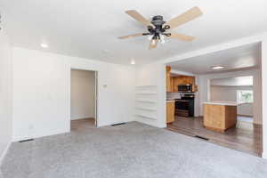 Unfurnished living room featuring light carpet and ceiling fan