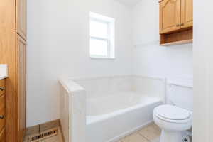 Bathroom with vanity, toilet, tile patterned floors, and a washtub