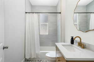 Full bathroom featuring tile patterned flooring, shower / bath combination with curtain, toilet, and vanity