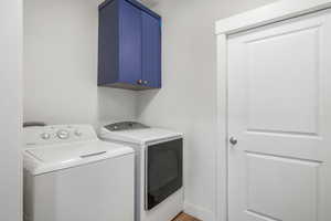 Laundry room with washer and clothes dryer, cabinets, and hardwood / wood-style floors