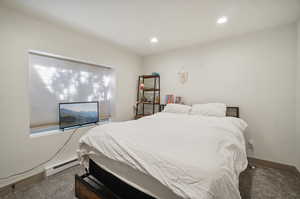 Carpeted bedroom featuring a baseboard heating unit