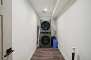 Laundry room featuring dark hardwood / wood-style flooring and stacked washer / drying machine