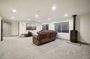 Living room featuring a wood stove and light colored carpet