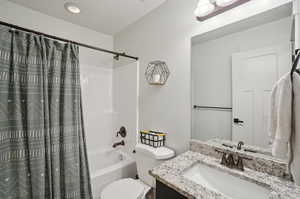 Full bathroom with vanity, shower / tub combo, and toilet