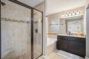 Bathroom with ceiling fan, vanity, shower with separate bathtub, and tile patterned flooring