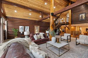 Living room featuring high vaulted ceiling, log walls, and beam ceiling