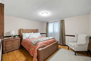 Bedroom with a textured ceiling and light wood-type flooring