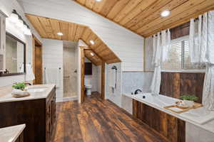 Bathroom with toilet, wooden walls, a tub to relax in, and hardwood / wood-style floors