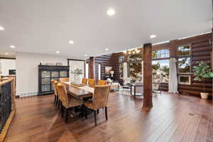 Dining area with dark hardwood / wood-style flooring and log walls