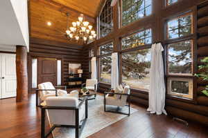 Living room with wooden ceiling, rustic walls, high vaulted ceiling, dark hardwood / wood-style flooring, and a notable chandelier