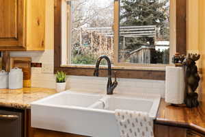 Room details featuring light stone countertops, stainless steel dishwasher, backsplash, and sink