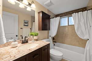 Full bathroom featuring shower / tub combo with curtain, vanity, and toilet