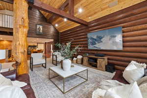 Living room featuring rustic walls, wooden ceiling, high vaulted ceiling, and beam ceiling