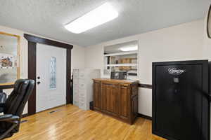 Home office with a textured ceiling and light hardwood / wood-style floors