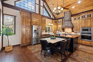 Kitchen featuring stainless steel appliances, sink, high vaulted ceiling, a center island with sink, and pendant lighting