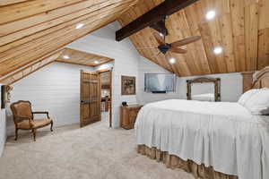 Bedroom featuring wooden ceiling, light carpet, wood walls, vaulted ceiling with beams, and ceiling fan