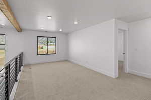 Spare room featuring light carpet and beam ceiling