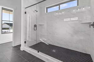 Bathroom with a shower with shower door and tile patterned floors