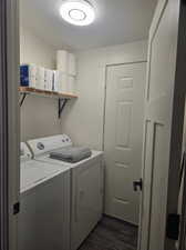 Laundry area with dark hardwood / wood-style flooring, washer and dryer, and a textured ceiling