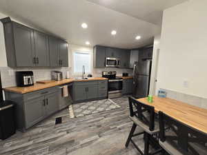 Kitchen with tasteful backsplash, stainless steel appliances, sink, dark hardwood / wood-style floors, and wood counters