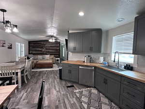 Kitchen featuring wooden counters, ceiling fan, wooden walls, and stainless steel dishwasher