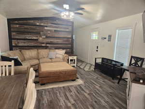 Living room with a textured ceiling, wood-type flooring, ceiling fan, and vaulted ceiling