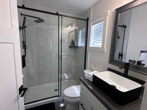 Bathroom with an enclosed shower, toilet, vanity, and a textured ceiling