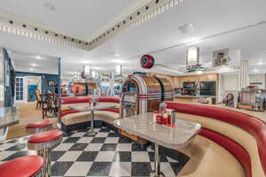 Tiled dining room featuring ceiling fan, a raised ceiling, and ornamental molding