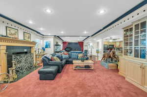 Living room featuring ornamental molding, carpet, and ceiling fan