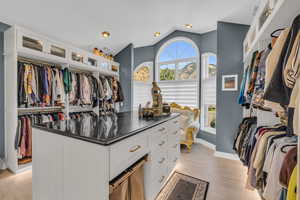 Walk in closet with light hardwood / wood-style flooring and lofted ceiling