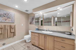 Bathroom with tile patterned flooring, walk in shower, toilet, and vanity