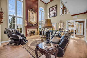 Living room featuring a tile fireplace, light hardwood / wood-style floors, and a towering ceiling