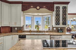 Kitchen featuring black electric cooktop, crown molding, tasteful backsplash, and sink