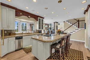 Kitchen with white cabinets, light stone countertops, light hardwood / wood-style flooring, and a kitchen island