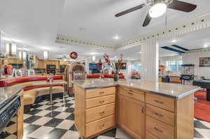 Kitchen with light tile patterned floors, light stone countertops, ceiling fan, and a tray ceiling