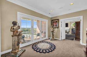 Doorway featuring light carpet and crown molding