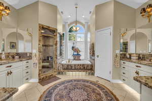 Master Bathroom with tile patterned flooring, lofted ceiling, independent shower and bath, and vanity