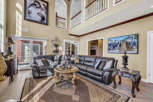 Living room with ornamental molding, hardwood / wood-style floors, and a towering ceiling