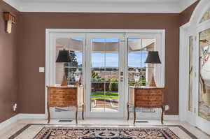 Doorway featuring plenty of natural light, crown molding, and light marble flooring