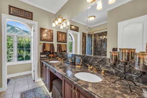 Bathroom with ornamental molding, dual vanity, tile patterned flooring, and walk in shower