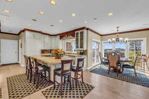 Dining room with light hardwood / wood-style flooring, crown molding, and a chandelier