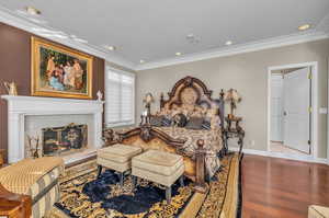 Master Bedroom featuring a tiled fireplace, crown molding, and hardwood / wood-style floors