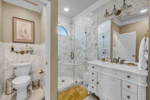 2nd Master Bathroom with a shower with shower door, tile patterned flooring, tile walls, toilet, and vanity