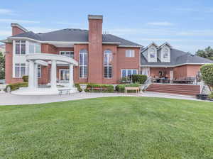 Rear view of property featuring a patio area, a lawn, and a wooden deck