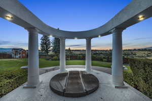 Patio terrace at dusk with a lawn and hot tub